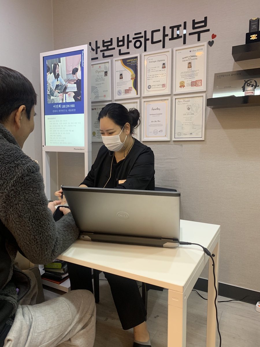 상담 책상에서 대표원장이 피부 상태를 보며 상담하는 모습